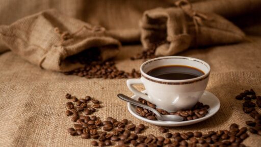 Xícara de café com grãos ao redor representando o mercado de café.