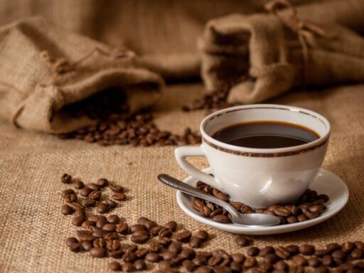 Xícara de café com grãos ao redor representando o mercado de café.
