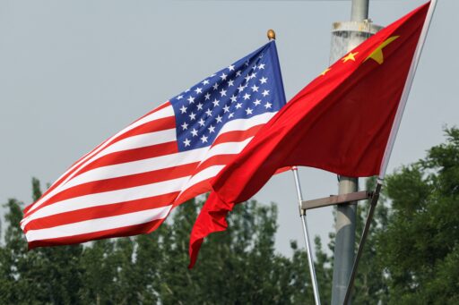 Bandeiras da China e dos Estados Unidos em uma rua chinesa.